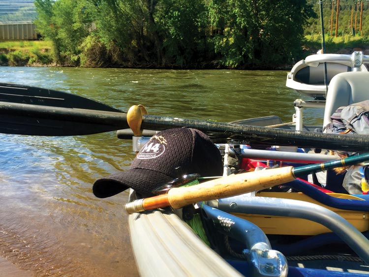 M4 Ranch Group hat sitting in a fishing boat on a river.