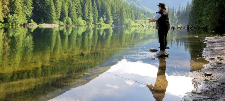 Woman fly-fishing, mountain lake