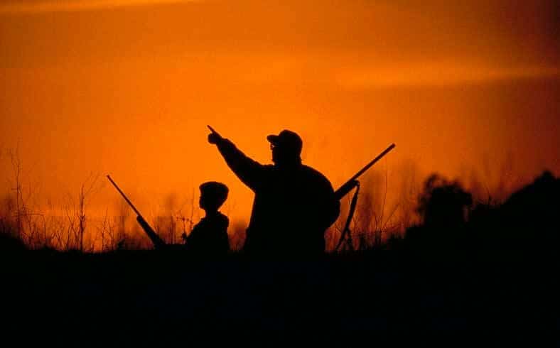 Generational hunters in field at sunset