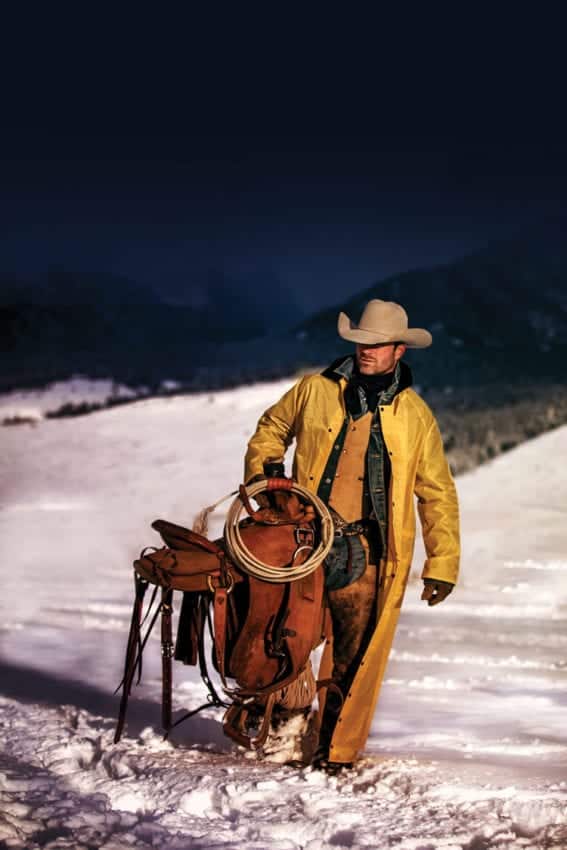 Chris Douglas - cowboy carrying saddle in snow