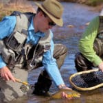 Two men putting a fish in a net