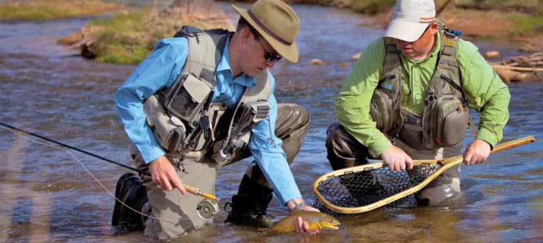 Two men putting a fish in a net