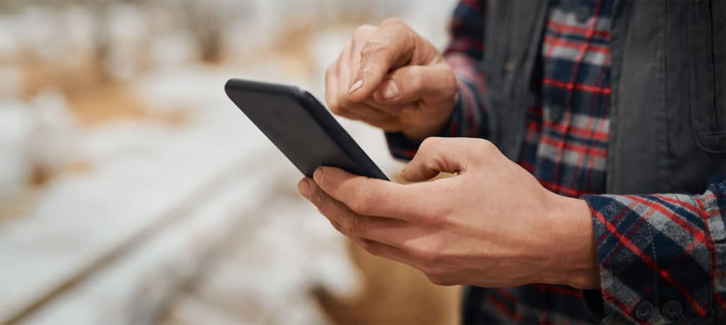 Image of a man using his mobile phone with a focus on his hands.