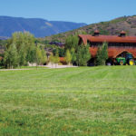 Western Heritage; barn next to a field in front of mountains