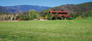 Western Heritage; barn next to a field in front of mountains