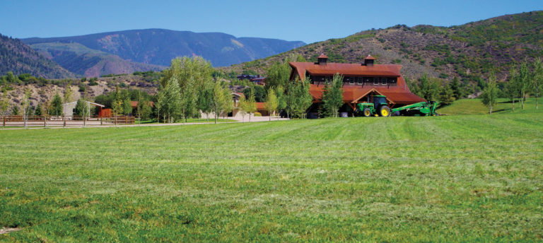 Western Heritage; barn next to a field in front of mountains