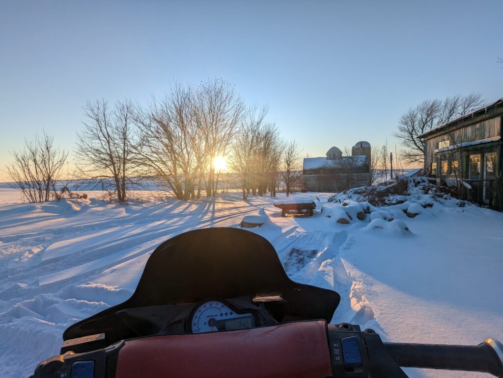 sunset snowmobile ride on rural property.